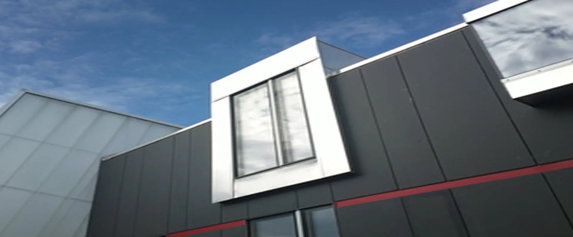 Detail der dunklen Metallfassade mit auskragendem Fensterrahmen